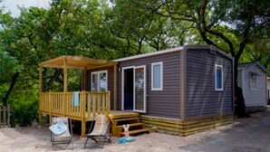 Eine kleine Holzhütte mit einer Terrasse, einer Veranda und einer Haustür.