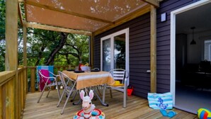 Eine Holzterrasse mit Tisch und Stühlen, ein kleiner aufblasbarer Pool und eine Tür, die in einen Innenraum führt.
