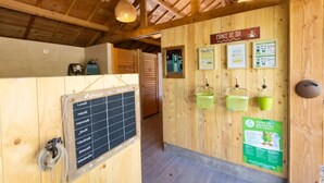 A wooden interior with a chalkboard listing room names, a sign for 'ESPACE DE TRI,' and green water dispensers.