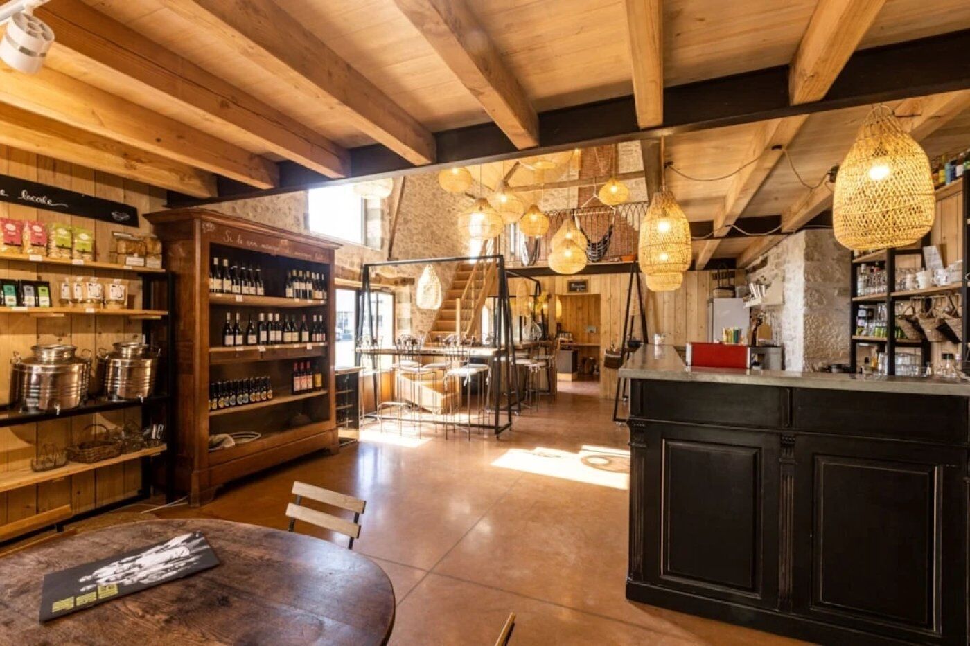 Un intérieur rustique avec des poutres en bois, un coin bar et des luminaires suspendus.