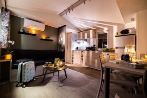 Ein modernes Wohnzimmer mit einer Couch, einem Esstisch und einer Küche im Hintergrund.