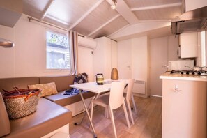 A compact living space with a kitchenette, a dining area, and a seating area with a sofa and a table. - Camping 4 étoiles - Parc aquatique - ccbfiab (Agde)