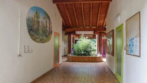 Un pasillo con techo de madera, suelo de baldosas, un cuadro y una puerta con marco verde.