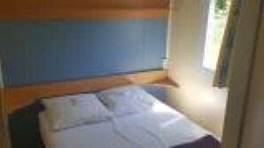 Una habitación pequeña con una cama, una ventana y una puerta.