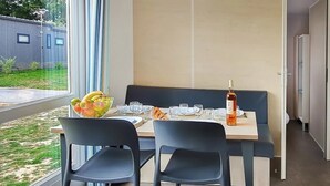 A modern dining area with a table set for two, a bowl of fruit, and a bottle of wine. - Camping 4 étoiles - Parc aquatique - ccbgdea (La Baule)