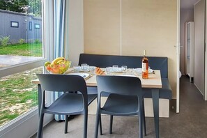 Ein moderner Essbereich mit einem Tisch für zwei Personen, einer Obstschale und einer Weinflasche.