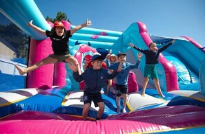 Kinder spielen auf einer bunten, aufblasbaren Hüpfburg.