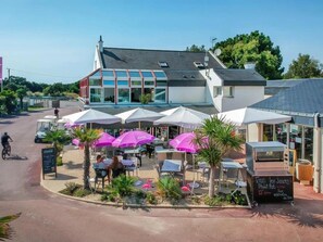 Ein Restaurant mit Außenbereich, Sonnenschirmen und einem Schild.