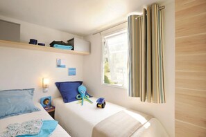 A bedroom with two beds, a window with curtains, a shelf with items, and wall art. - Camping 4 étoiles - Parc aquatique - ccbgdeb (La Baule)