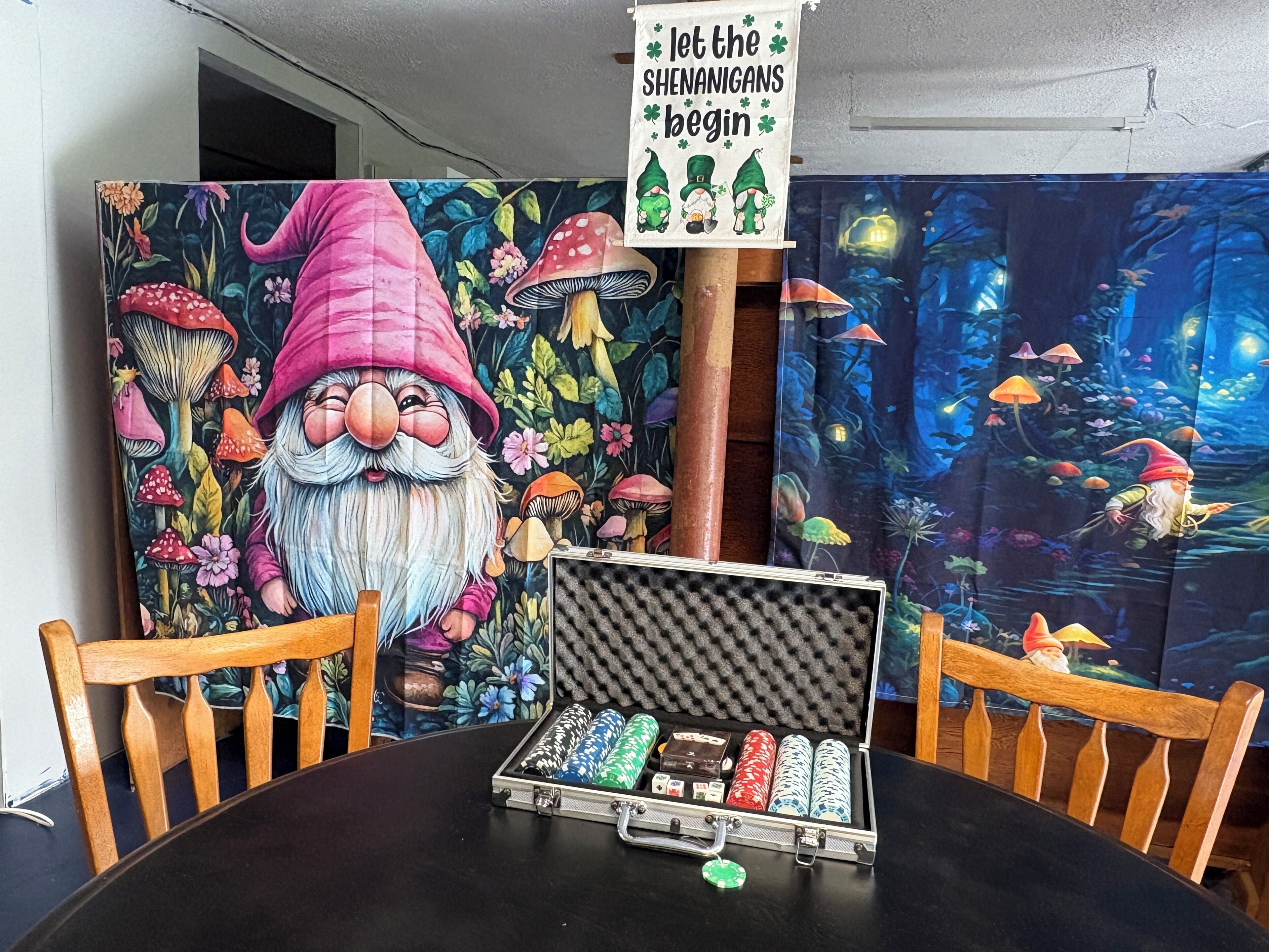 A dining table with a gnome-themed painting, a sign, and a poker chip case.