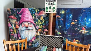Un tavolo da pranzo con un quadro a tema gnomi, un cartello e un portasettoli da poker.
