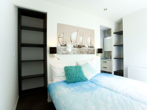 A bedroom with a bed, a wall-mounted artwork, a nightstand, a mirror, and a wardrobe. - Holiday Home in Breskens With Terrace (Breskens)