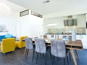 A modern dining area with a wooden table, grey upholstered chairs, and a blue sofa. - Holiday Home in Breskens With Terrace (Breskens)