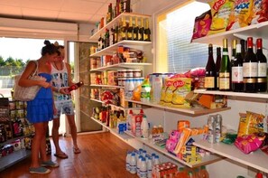 Un magasin dont les étagÚres sont remplies de divers produits, notamment des collations, des boissons et des articles ménagers.