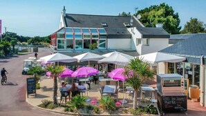 Un ristorante con posti a sedere all'aperto, ombrelloni e un cartello.