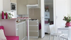 Un ambiente compatto con angolo cottura, zona pranzo e camera da letto.