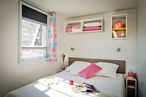 Ein Schlafzimmer mit einem Bett, Nachttischen, einem Fenster und Wandregalen.