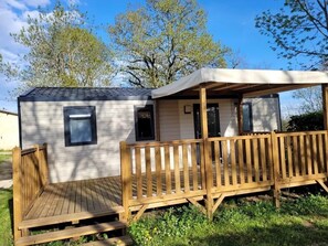 Eine kleine Holzhütte mit einer Holzterrasse, einer Veranda und einem Fenster.