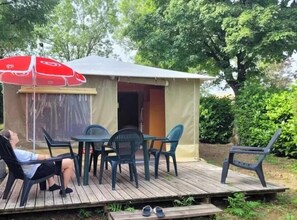 Ein kleines, eingeschossiges Gebäude mit einer Terrasse, einem Tisch und Stühlen sowie einem roten Sonnenschirm.