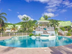 A swimming pool with a gazebo, palm trees, and a green-roofed building. - Palmaya · Cozy tropical retreat, beach & pool (Anse Marcel)