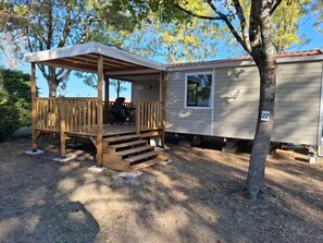 A mobile home with a wooden deck and a covered porch. - Camping 3 étoiles - Piscine  - ccbfi0i (Mauroux)