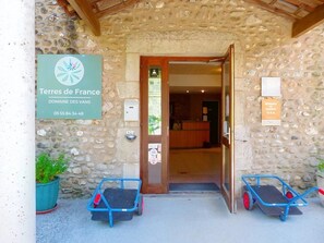 A stone building entrance with a sign for 'Terres de France Domaine des Vans' and a reception area visible inside. - Camping 3 étoiles - Piscine  - ccbc0gc (Chambonas)