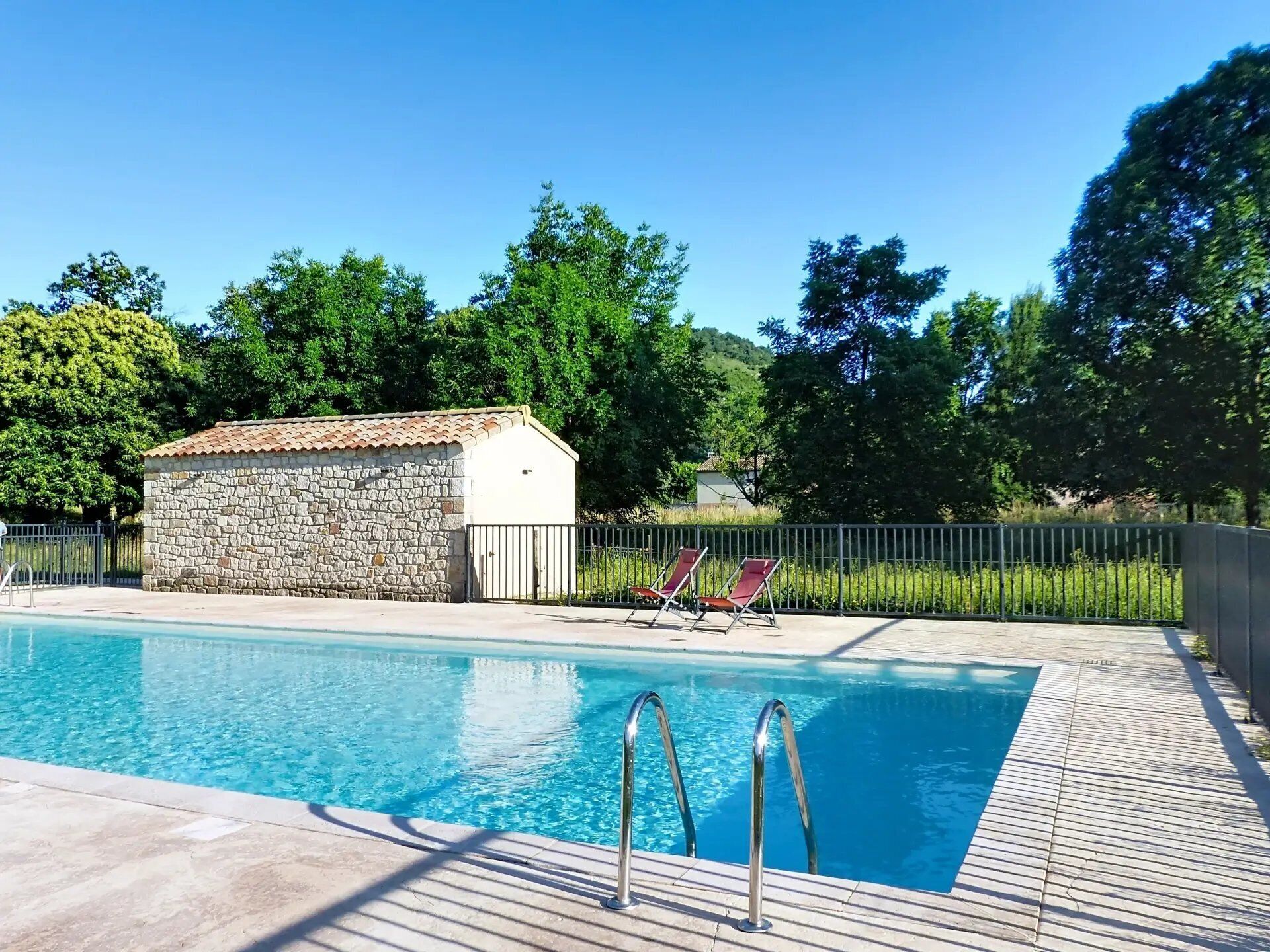 Una piscina con un edificio de piedra y sillas de descanso.