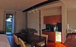 Ein modernes Hotelzimmer mit Essbereich, einer Küchenzeile und Blick durch eine Glastür.