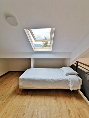 Ein Zimmer mit Oberlicht, einem Bett und Blick ins Freie.