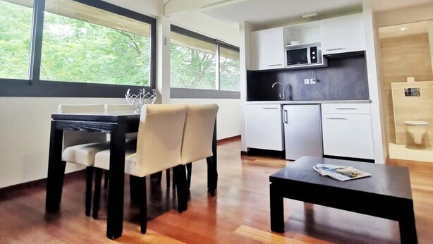 Un interior moderno con comedor, cocina y un gran ventanal que ofrece vistas a zonas verdes.