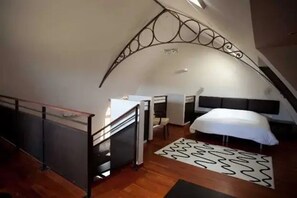 A bedroom with a curved ceiling, a bed, a desk, and a chair. - Appartement 3 étoiles - ccbefb0 (Saint-Lizier)