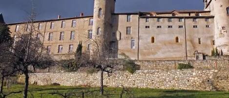 A large, historic building with multiple towers and a stone wall.