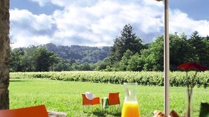 Ein Essbereich im Freien mit Tisch, Stühlen und Sonnenschirm.