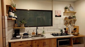 Moderni keittiö, jossa on suuri litteänäyttöinen televisio, sisäänrakennettu uuni ja erilaisia keittiölaitteita.