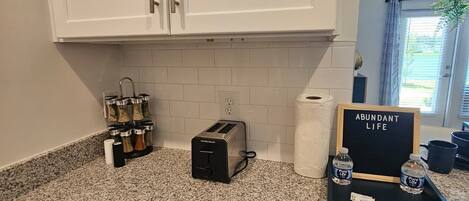Eine Küche mit weißen Schränken, einer Granit Arbeitsplatte, einem Toaster, einer Kaffeemaschine und einem Schild mit der Aufschrift 'ABUNDANT LIFE'.