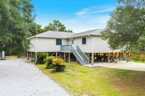 Ein zweistöckiges Haus mit überdachter Veranda, einer Treppe und einer Garage.