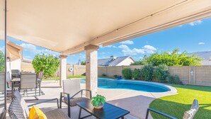 Eine Außenpatio mit Pool, Korbmöbeln und einer überdachten Sitzgelegenheit.