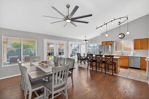 A spacious kitchen with wooden cabinets, a refrigerator, and a dining area with a table and chairs. - New Mesa Family Oasis, Htd Pool, Games, Mini Golf! (Mesa)