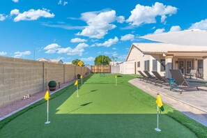 A golf course with a clear sky, a brick wall, and a building with outdoor seating. - New Mesa Family Oasis, Htd Pool, Games, Mini Golf! (Mesa)