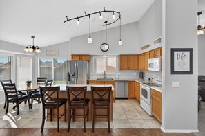 A modern kitchen with wooden cabinets, a central island, and pendant lighting. - New Mesa Family Oasis, Htd Pool, Games, Mini Golf! (Mesa)