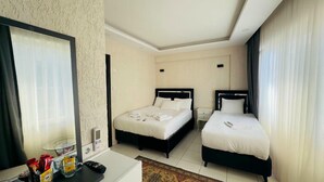 A hotel room with two beds, a desk, a chair, and a small table with snacks. - Valeria Homes Sultanahmet (fatih)