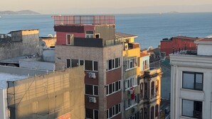 A cityscape with buildings, a view of the sea, and a sign for a property management company. - Valeria Homes Sultanahmet (fatih)
