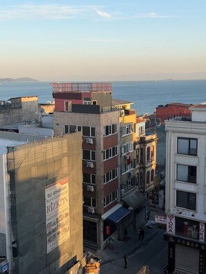 A cityscape with buildings, a view of the sea, and a sign for a property management company. - Valeria Homes Sultanahmet (fatih)