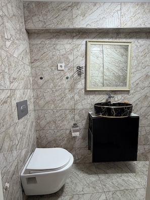 A bathroom with a toilet, a sink with a marble basin, and a mirror with a gold frame. - Valeria Homes Sultanahmet (fatih)