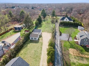 A residential area with houses, a central path, and surrounding greenery. - Waterfront Retreat w/ Dock & Modern Design (Center Moriches)