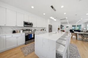 Una cocina moderna con muebles blancos, electrodomésticos de acero inoxidable y una isla de mármol.