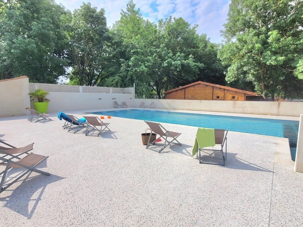 An outdoor swimming pool with lounge chairs and a brick building in the background.