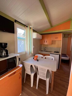A compact kitchen with a dining table, chairs, a microwave, and a small refrigerator.