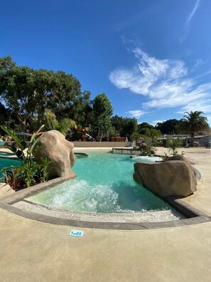 A swimming pool with rock formations and a clear blue sky.