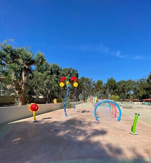 A playground with colorful equipment, trees, and a clear sky.